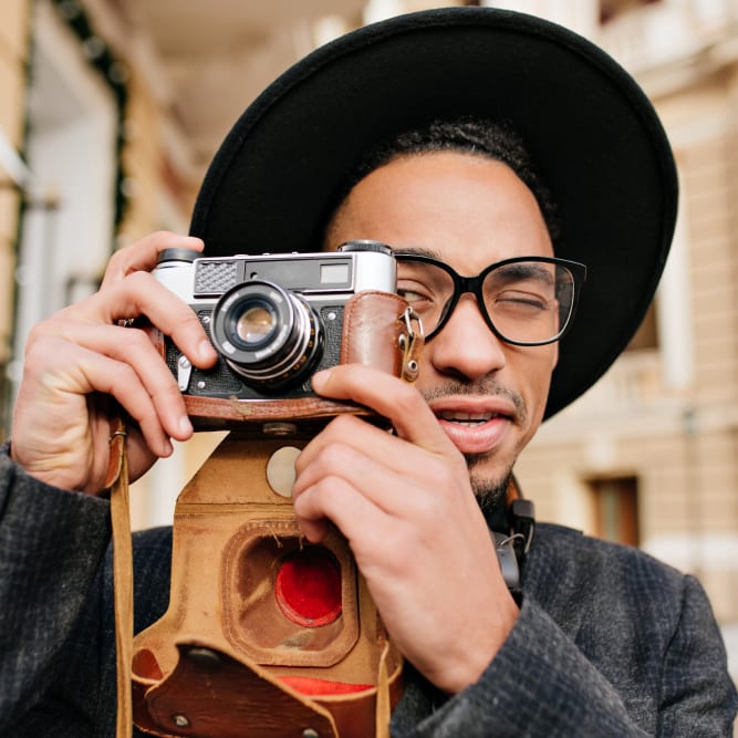 man holding camera taking a photo wearing black glasses